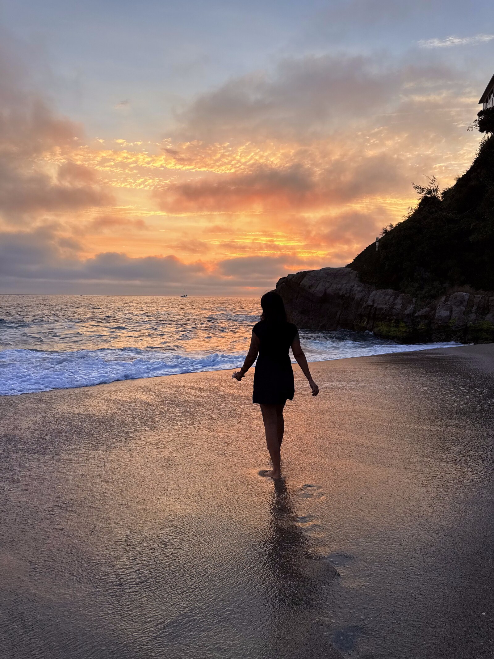 Sunset beach with woman walking toward the ocean